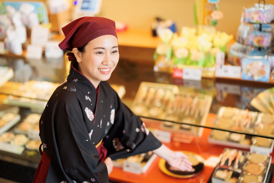 和服を着た女性が展示ケースの前でポーズをとっています。