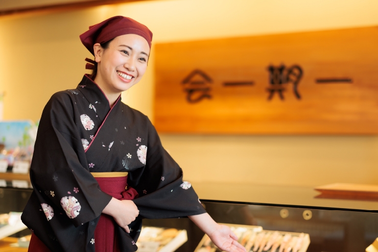 和服を着た女性が展示ケースの前でポーズをとっています。