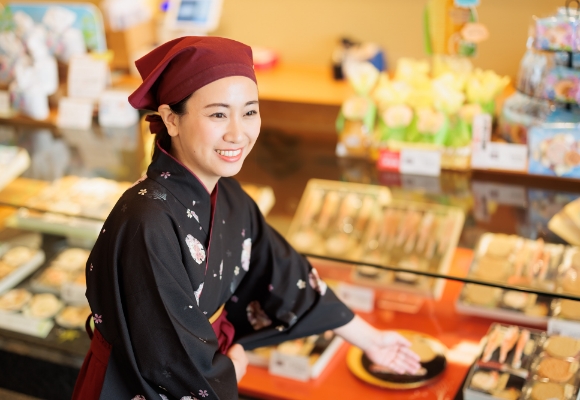 食品ディスプレイの前に立つ着物姿の女性。