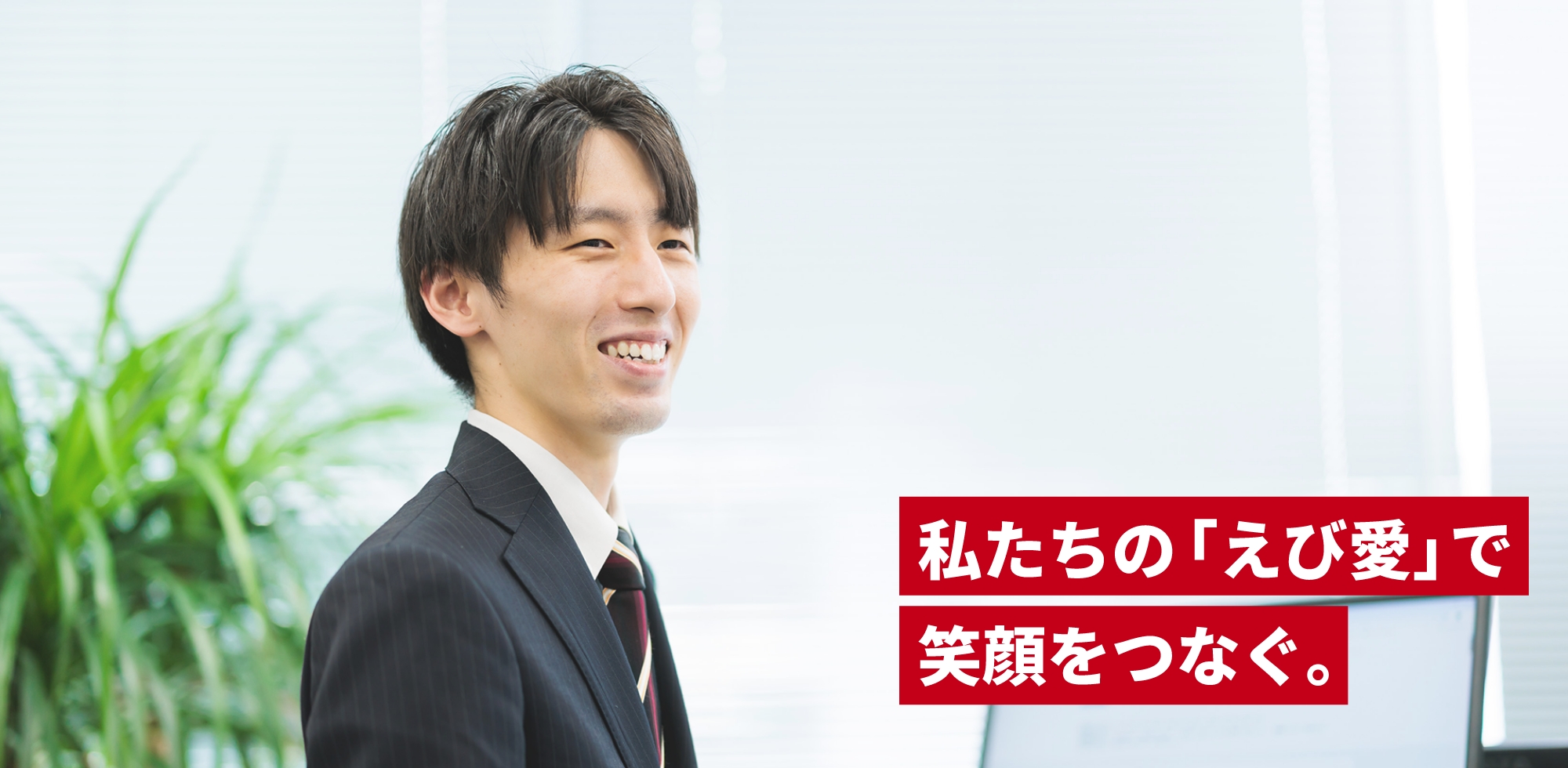 笑顔の男性がスーツを着て、ノートパソコンを手に持っています。