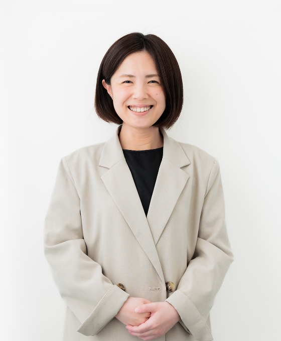ベージュのジャケットと黒いトップを着た女性が写っています。