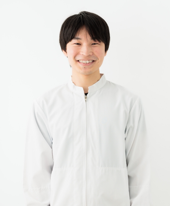 白いジャケットを着た男性が白い背景の前に立っています。