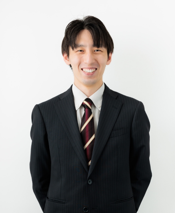 スーツ姿の若い男性が微笑んでいる。