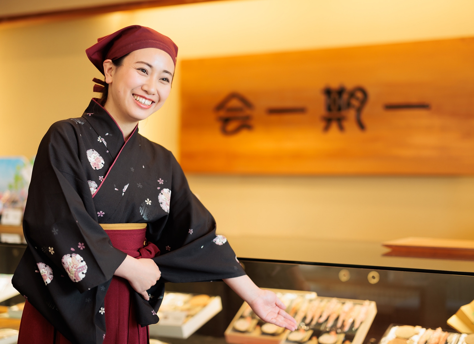 展示ケースの前に立つ、伝統的な着物を着た女性の姿。