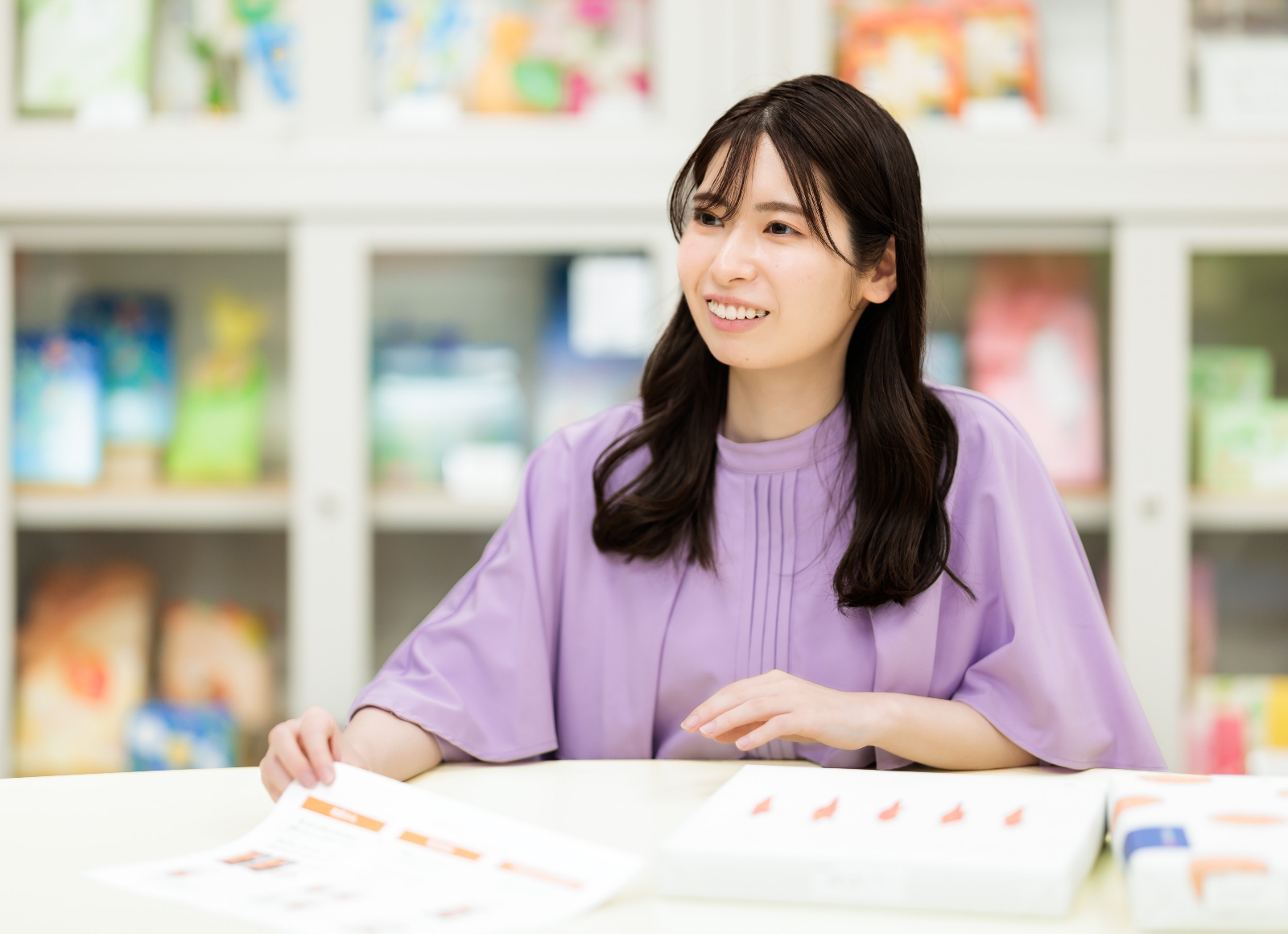 女性がテーブルに座り、手元の紙に目を向けています。