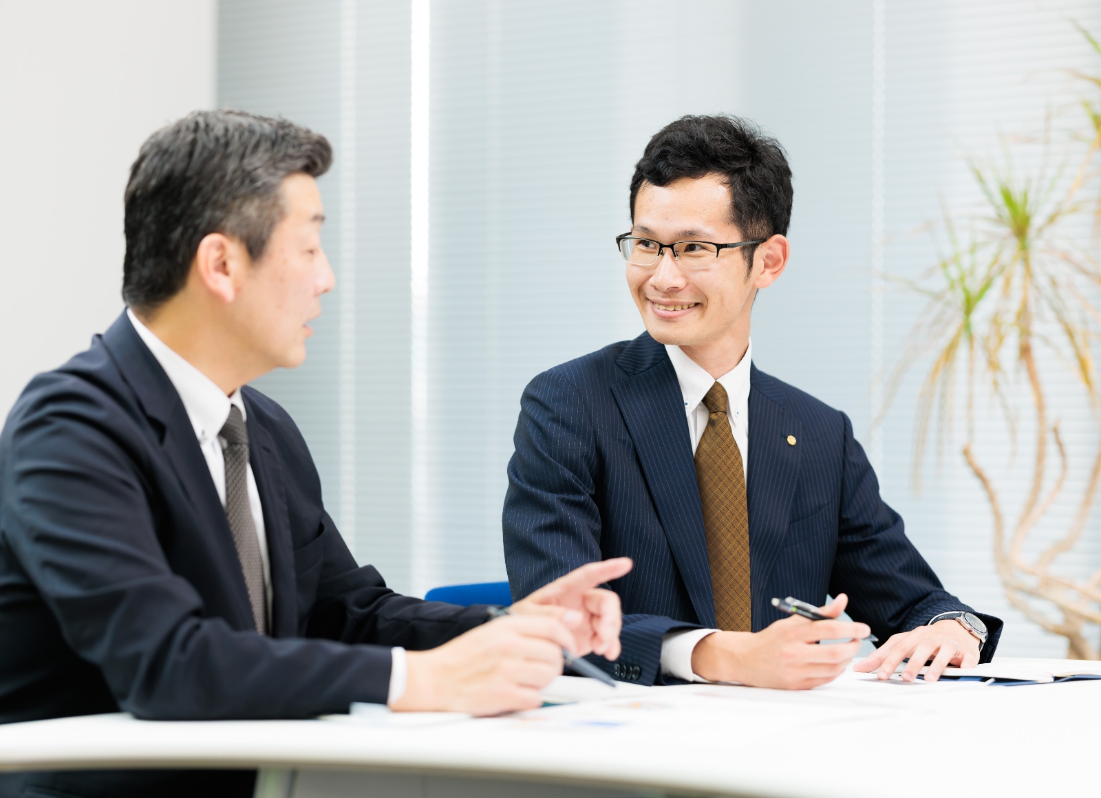 テーブルに座る二人のアジア人ビジネスマンの姿。