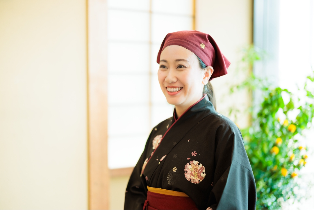 笑顔の女性が伝統的な日本の服装を身に着けている。