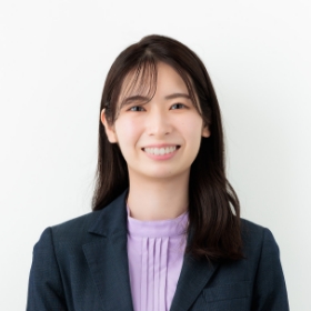 笑顔の女性がビジネススーツを着用している様子を捉えた画像です。