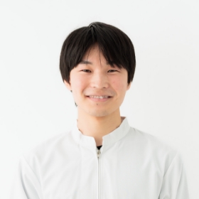 笑顔の男性が白いシャツを着て、明るい表情をしています。