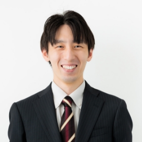 スーツ姿の男性が笑顔でカメラを見つめています。